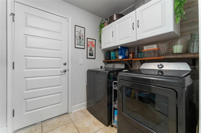 laundry room featuring light tile patterned floors, separate washer and dryer, and cabinets