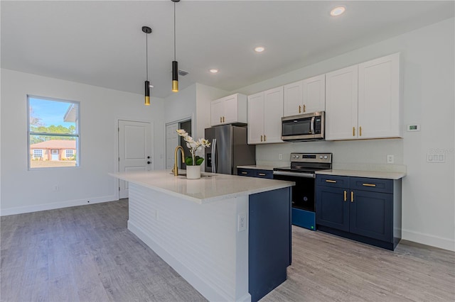 kitchen featuring blue cabinets, white cabinetry, an island with sink, hanging light fixtures, and stainless steel appliances