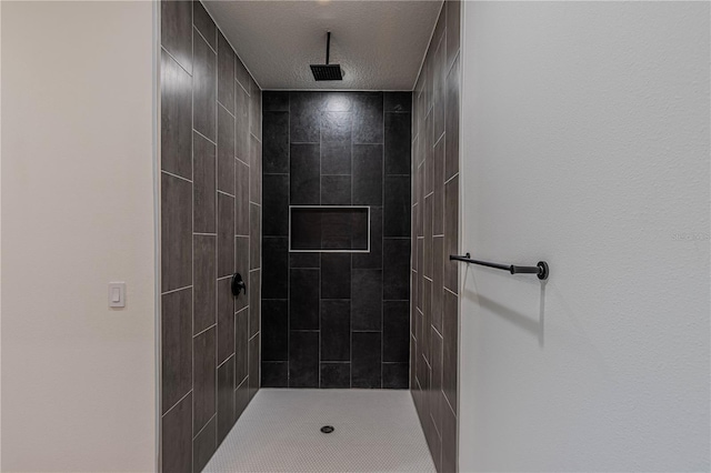 bathroom with tiled shower and a textured ceiling