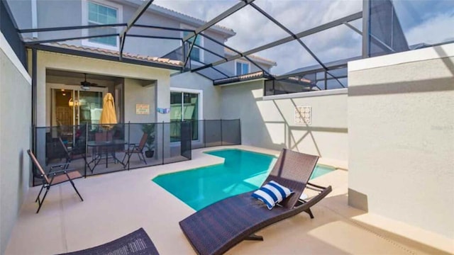 view of swimming pool with ceiling fan, a lanai, and a patio