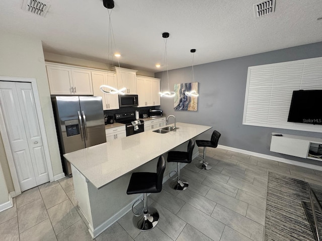 kitchen featuring a kitchen bar, sink, decorative light fixtures, a center island with sink, and appliances with stainless steel finishes