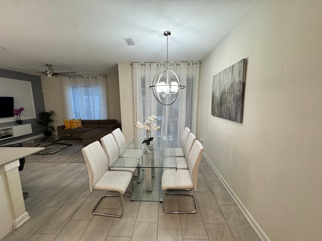 dining area with ceiling fan with notable chandelier and a textured ceiling