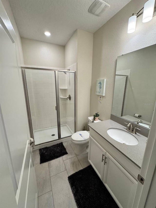 bathroom with toilet, vanity, a textured ceiling, and walk in shower