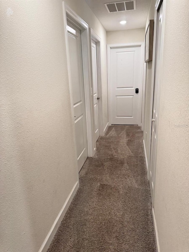 hallway featuring dark carpet