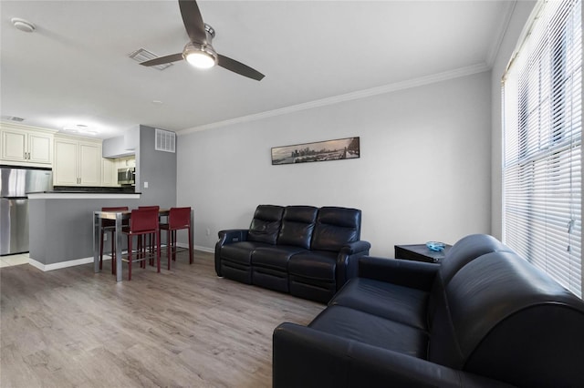 living room featuring ceiling fan, ornamental molding, and light hardwood / wood-style floors