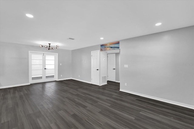 spare room featuring dark wood-type flooring and a chandelier