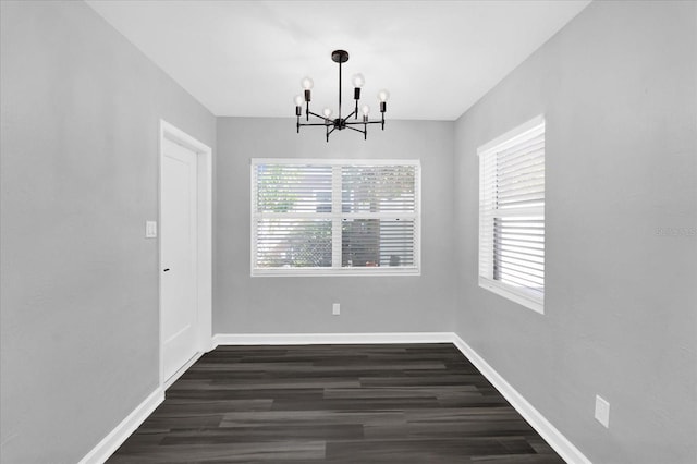 unfurnished dining area featuring dark wood-type flooring, a chandelier, and a wealth of natural light