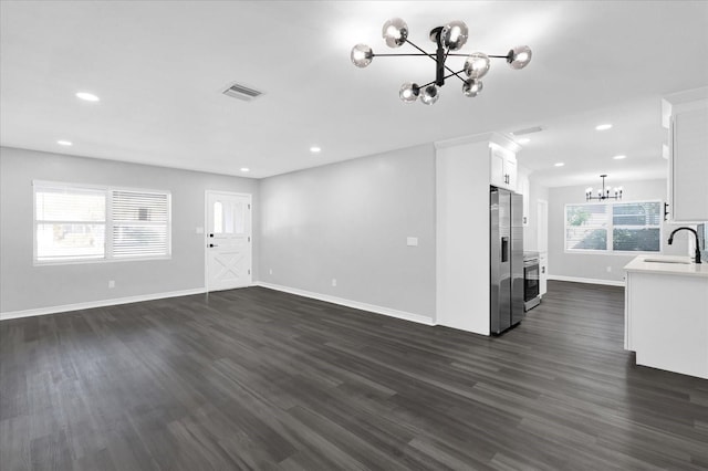 unfurnished living room with sink, a notable chandelier, and dark hardwood / wood-style floors