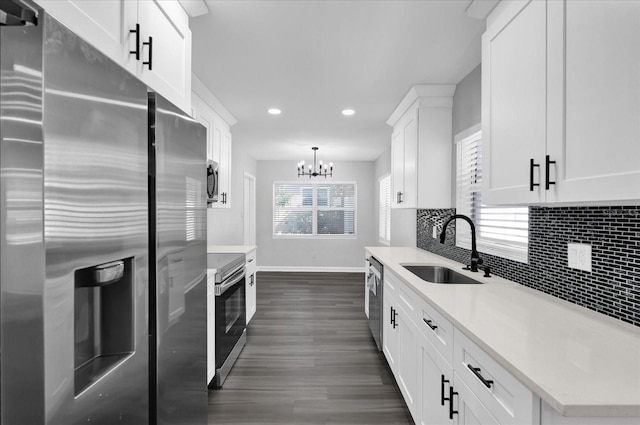 kitchen with decorative light fixtures, tasteful backsplash, white cabinetry, sink, and stainless steel appliances