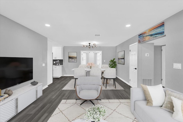 living room with dark wood-type flooring and a chandelier