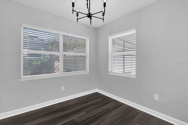 unfurnished room with dark hardwood / wood-style floors and a notable chandelier