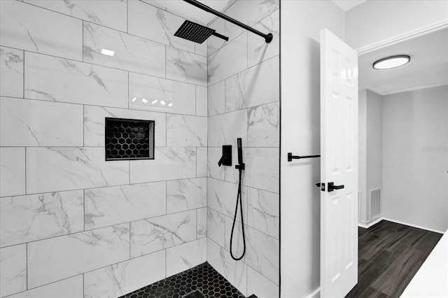 bathroom with hardwood / wood-style floors and a tile shower