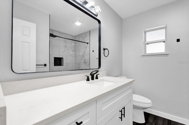 bathroom with wood-type flooring, toilet, vanity, and a tile shower