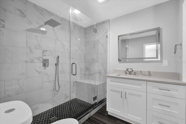 bathroom featuring vanity, hardwood / wood-style floors, a shower with shower door, and toilet