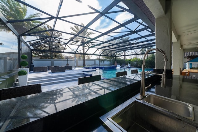 view of patio with pool water feature, sink, and glass enclosure