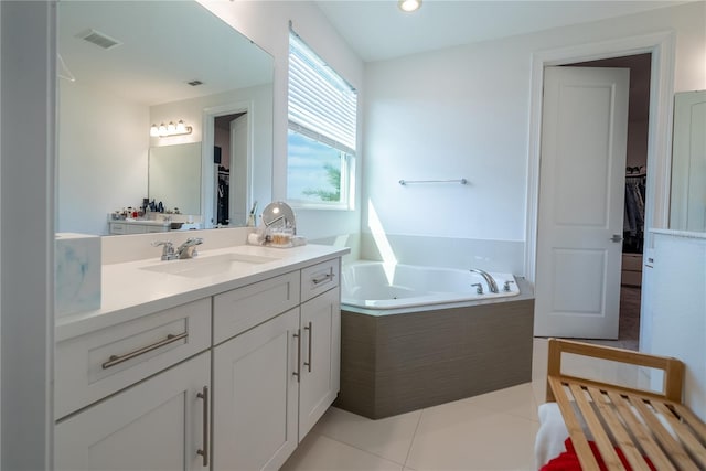 bathroom featuring vanity, a relaxing tiled tub, and tile patterned floors