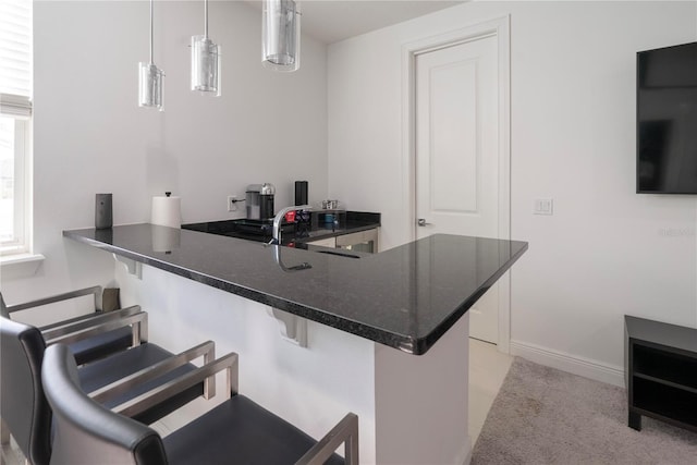 kitchen with sink, a kitchen breakfast bar, decorative light fixtures, light colored carpet, and kitchen peninsula