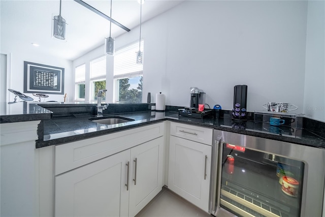 kitchen featuring wine cooler, sink, decorative light fixtures, dark stone countertops, and white cabinets