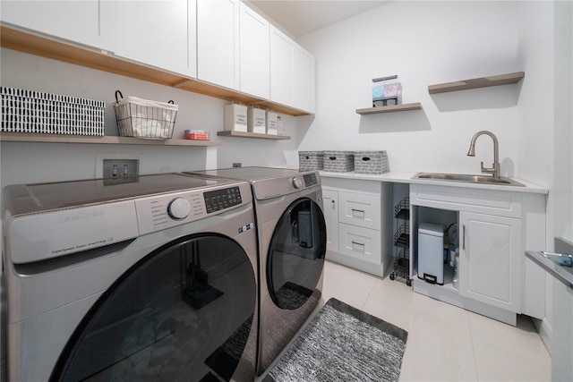 washroom featuring light tile patterned flooring, cabinets, washer and clothes dryer, and sink