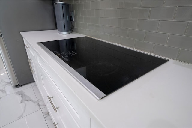 interior details featuring stainless steel refrigerator, black electric stovetop, and white cabinets