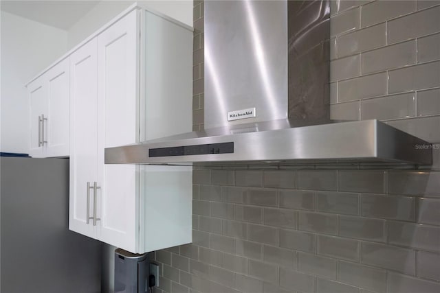 interior details with white cabinets and wall chimney range hood