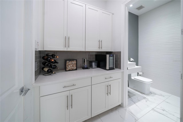 bar with white cabinetry and decorative backsplash