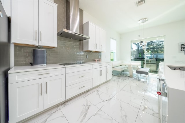 kitchen with white cabinetry, black electric stovetop, decorative backsplash, and wall chimney exhaust hood