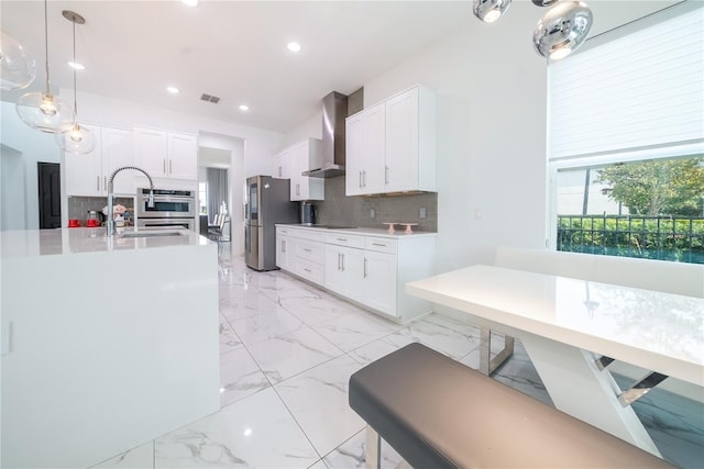 kitchen with wall chimney exhaust hood, stainless steel appliances, and white cabinets