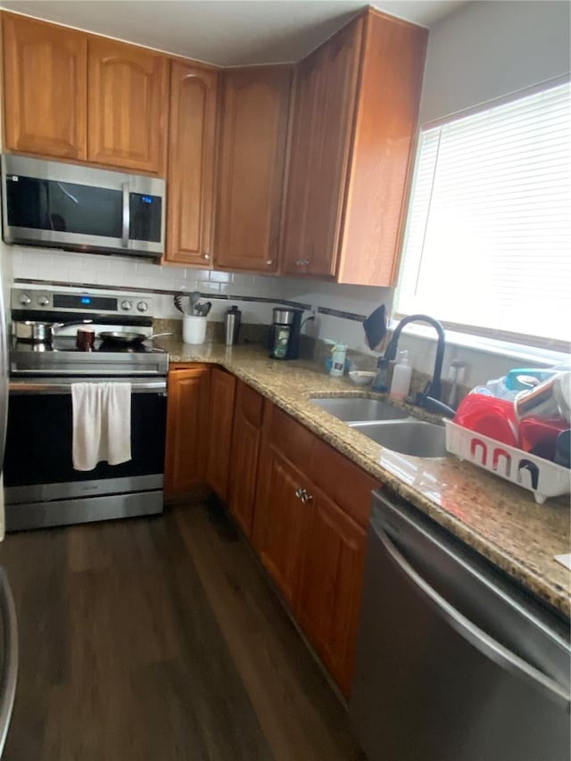 kitchen featuring dark hardwood / wood-style floors, tasteful backsplash, sink, light stone counters, and stainless steel appliances