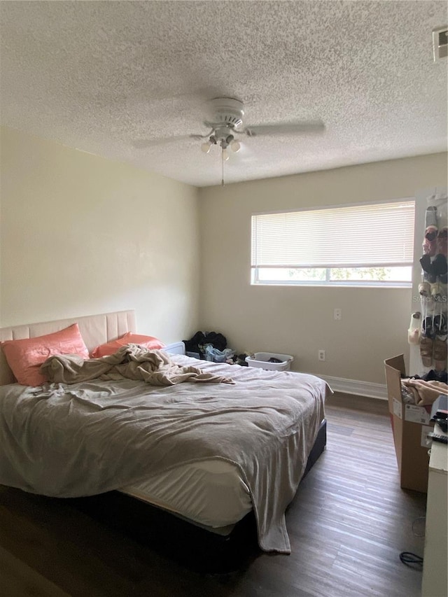 bedroom featuring dark hardwood / wood-style floors, a textured ceiling, and ceiling fan