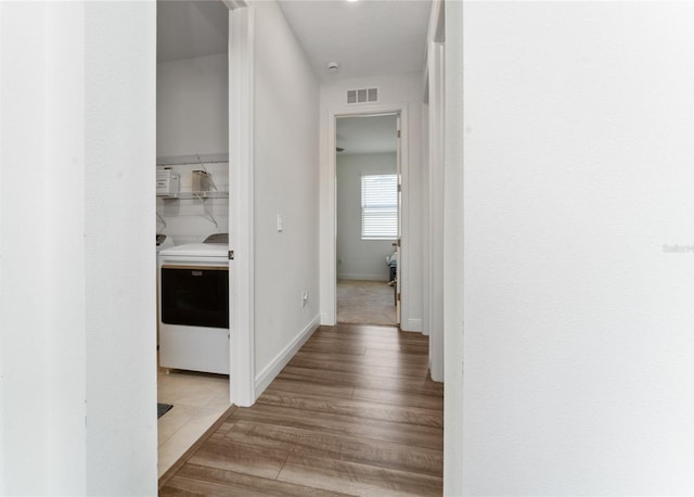 hallway with wood-type flooring and washer / dryer