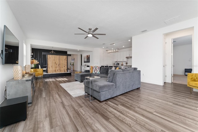 living room featuring hardwood / wood-style flooring, ceiling fan, and a textured ceiling