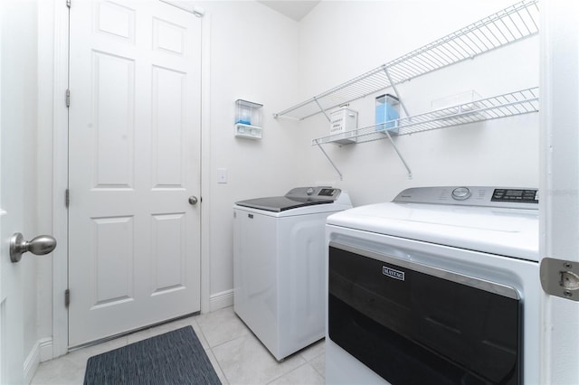 clothes washing area featuring light tile patterned floors and washer and dryer