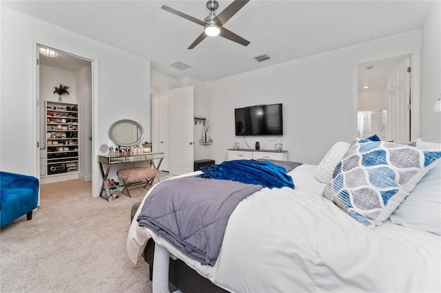 carpeted bedroom with a walk in closet and ceiling fan