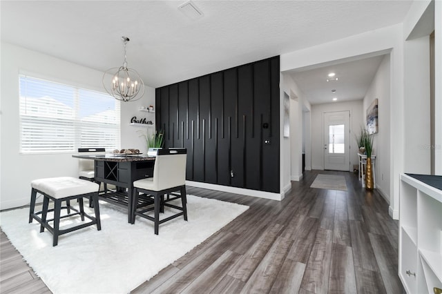 dining room with dark wood-type flooring, a textured ceiling, and a chandelier