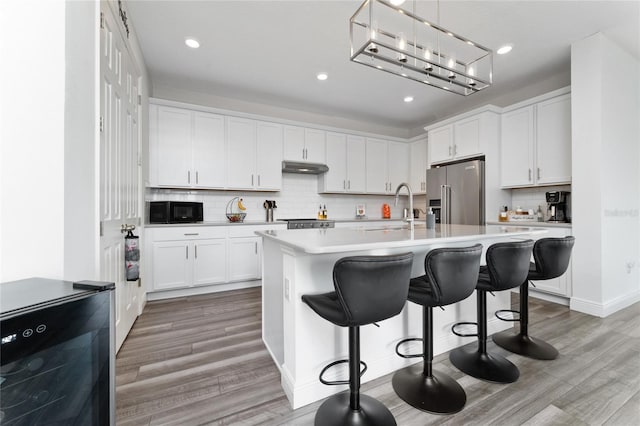 kitchen featuring a kitchen island with sink, high quality fridge, and white cabinets