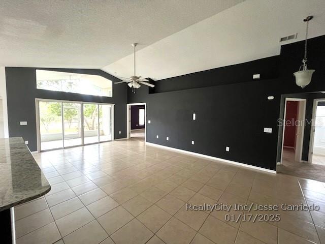 unfurnished living room featuring ceiling fan, high vaulted ceiling, a textured ceiling, and light tile patterned floors