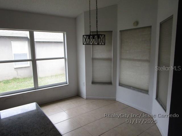 unfurnished dining area with light tile patterned flooring and vaulted ceiling