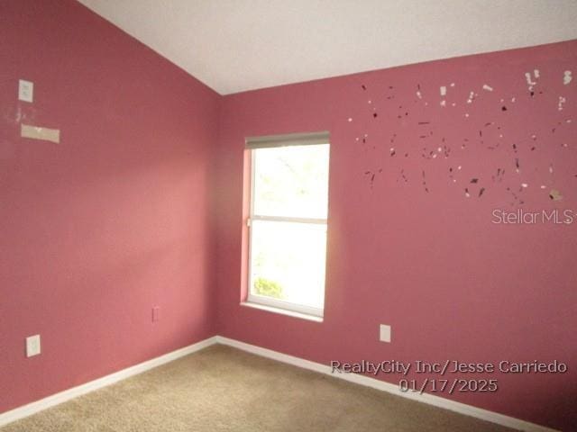 carpeted spare room with lofted ceiling