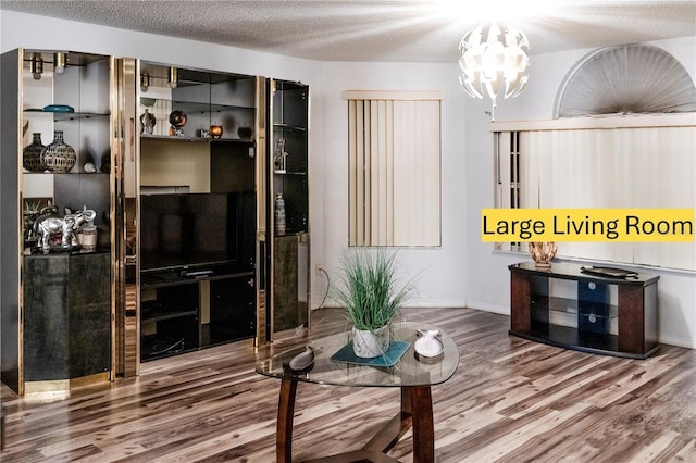 living room featuring hardwood / wood-style flooring, a textured ceiling, and a notable chandelier