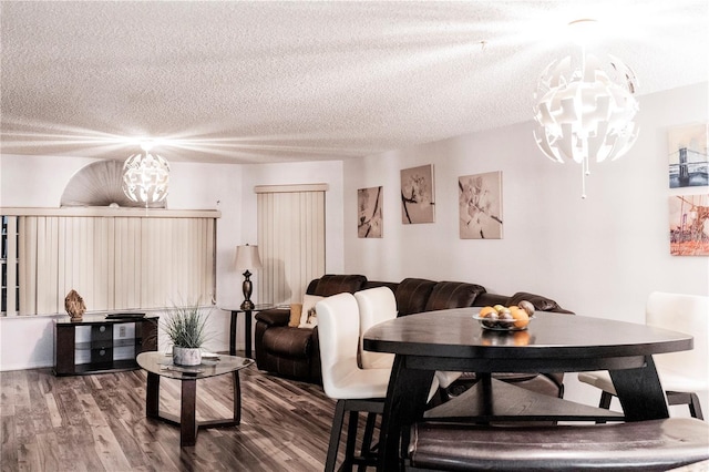 living room with dark hardwood / wood-style flooring, a textured ceiling, and a notable chandelier