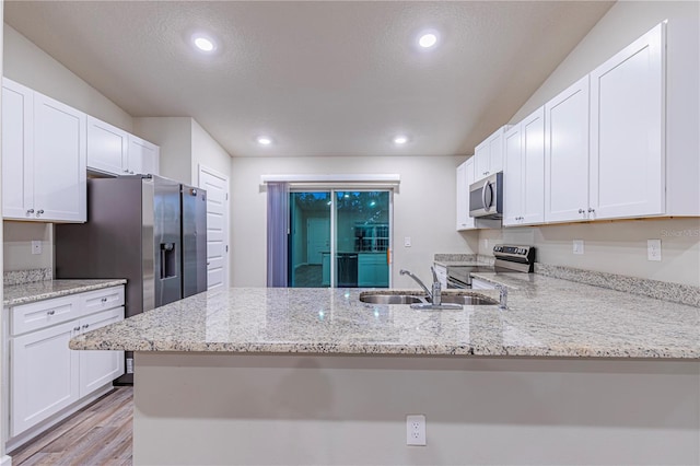 kitchen featuring kitchen peninsula, white cabinets, and appliances with stainless steel finishes