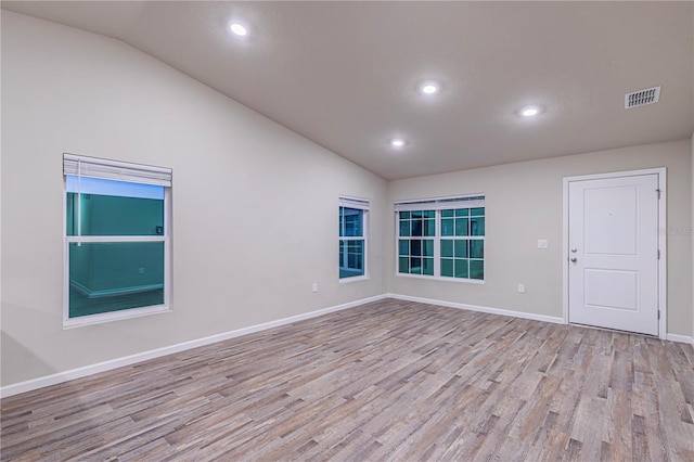 unfurnished room featuring lofted ceiling and light hardwood / wood-style floors