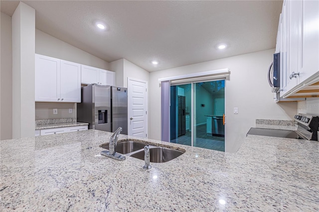 kitchen featuring sink, white cabinetry, light stone counters, a textured ceiling, and stainless steel appliances