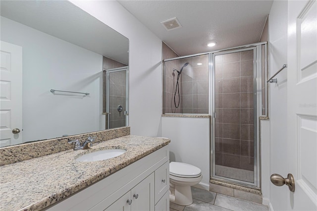 bathroom with tile patterned flooring, vanity, a shower with door, and toilet