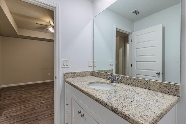 bathroom with ceiling fan, hardwood / wood-style floors, vanity, and a textured ceiling