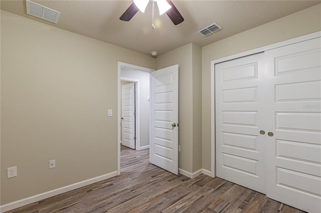 unfurnished bedroom with ceiling fan, a closet, hardwood / wood-style floors, and a textured ceiling