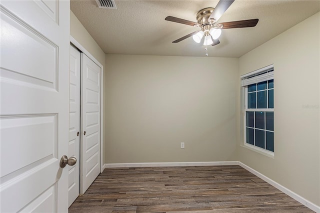 unfurnished bedroom with ceiling fan, a closet, dark hardwood / wood-style flooring, and a textured ceiling