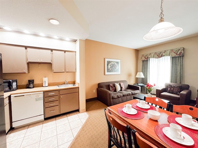 kitchen with white dishwasher, hanging light fixtures, light tile patterned floors, and sink