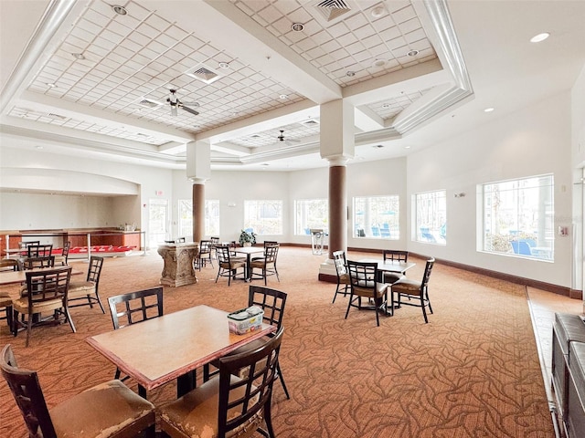 carpeted dining room with decorative columns, coffered ceiling, a towering ceiling, and ceiling fan